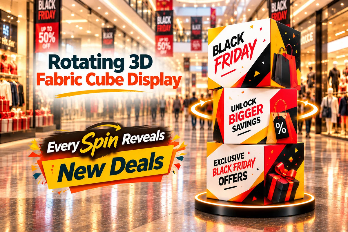 Promotional retail display in a shopping mall featuring three stacked rotating 3D fabric cubes with Black Friday sale text, set on a circular base in a blurred store interior.